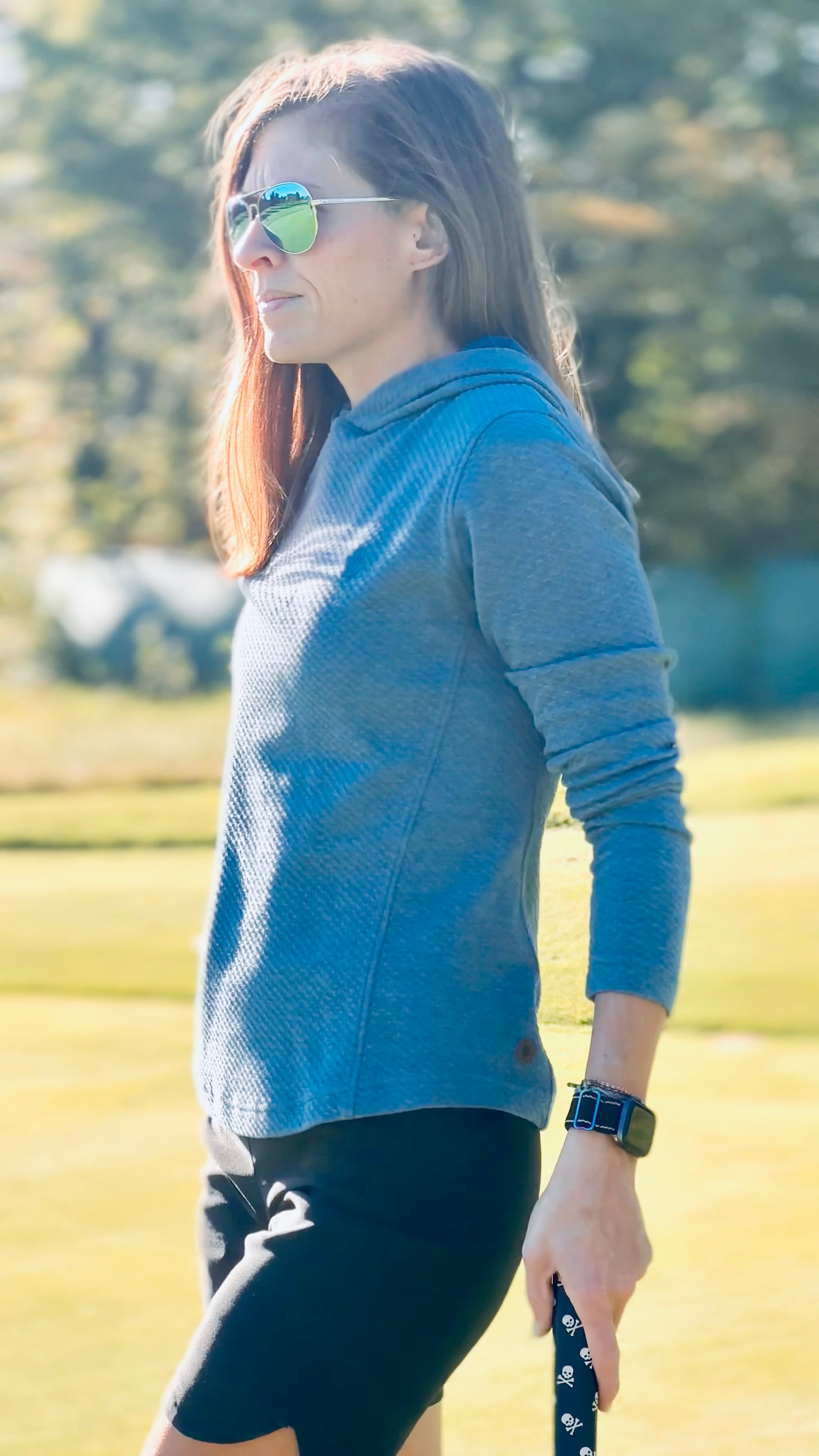 A woman wearing a blue Bellfield Hoodie on the golf course