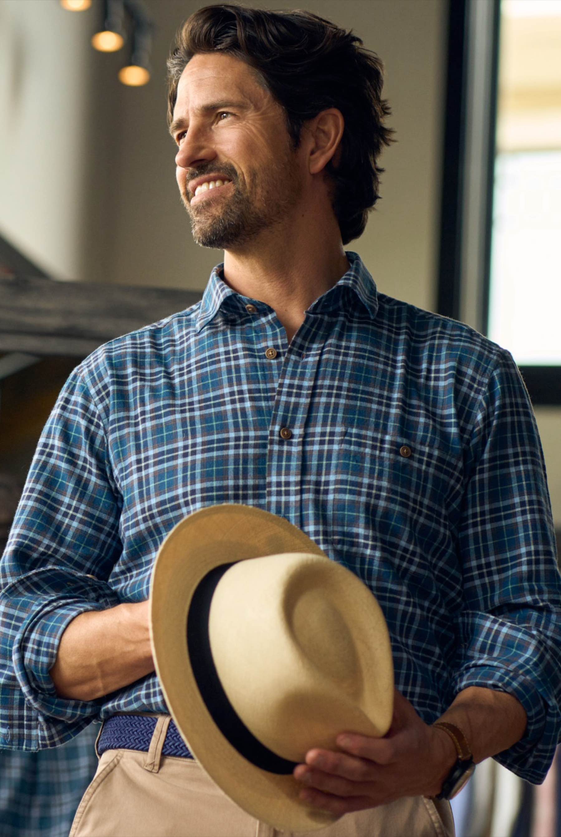 Man wearing a blue plaid Turtleson sport shirt and holding a hat