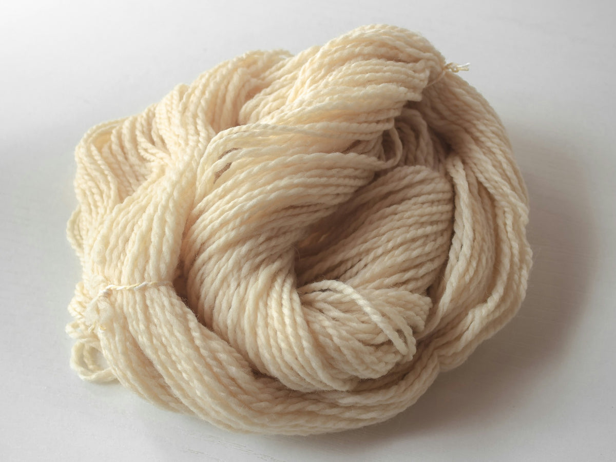 A softly twisted skein of cream wool yarn